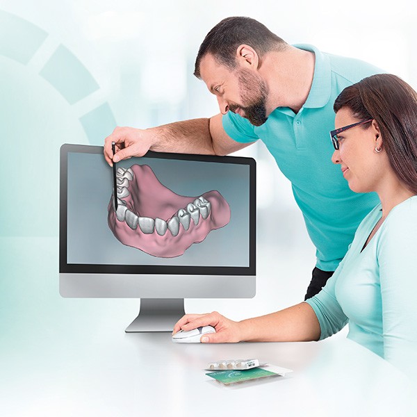 Two dental technicians working on the digital design of a denture